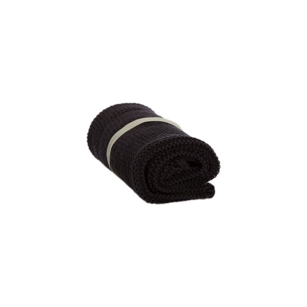 A rolled-up grey knitted washcloth on white background