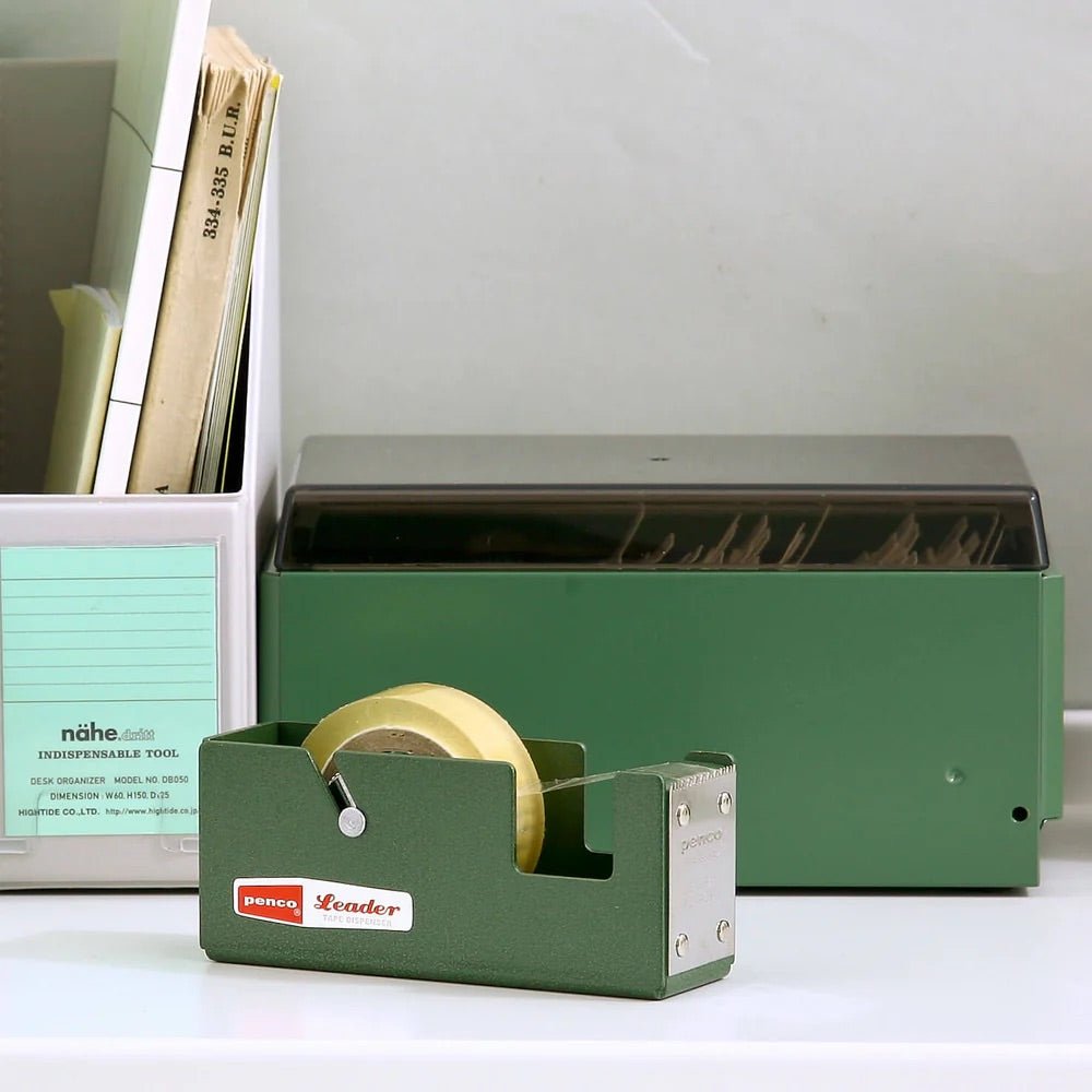 Green tape dispenser with a roll of tape on a white surface.