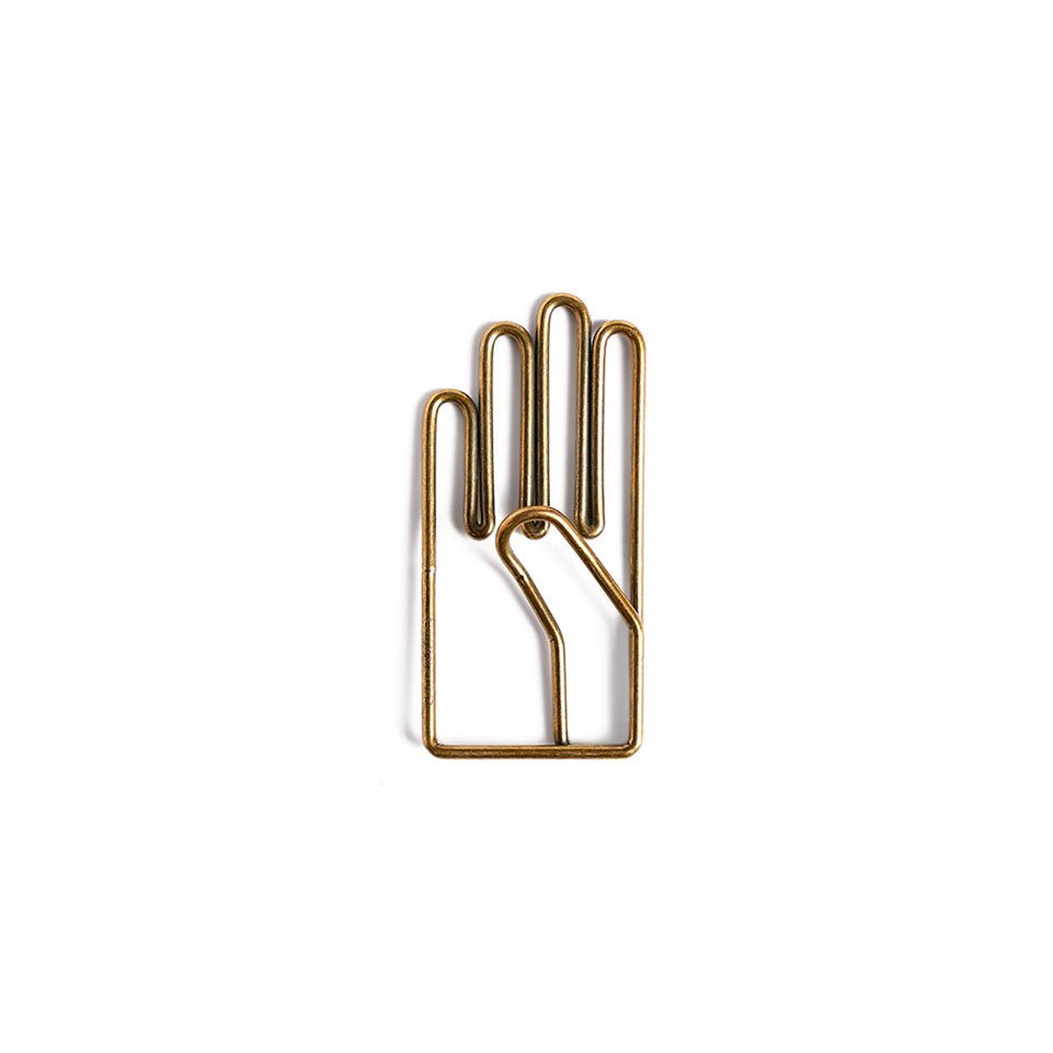 A metal clip with brass coloring, shaped like a hand.