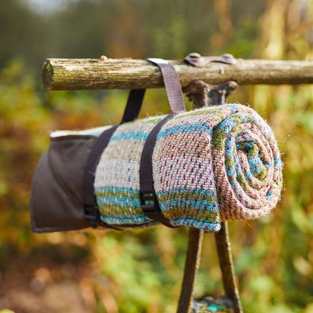 A rolled picnic blanket hanging by its carrying strap.