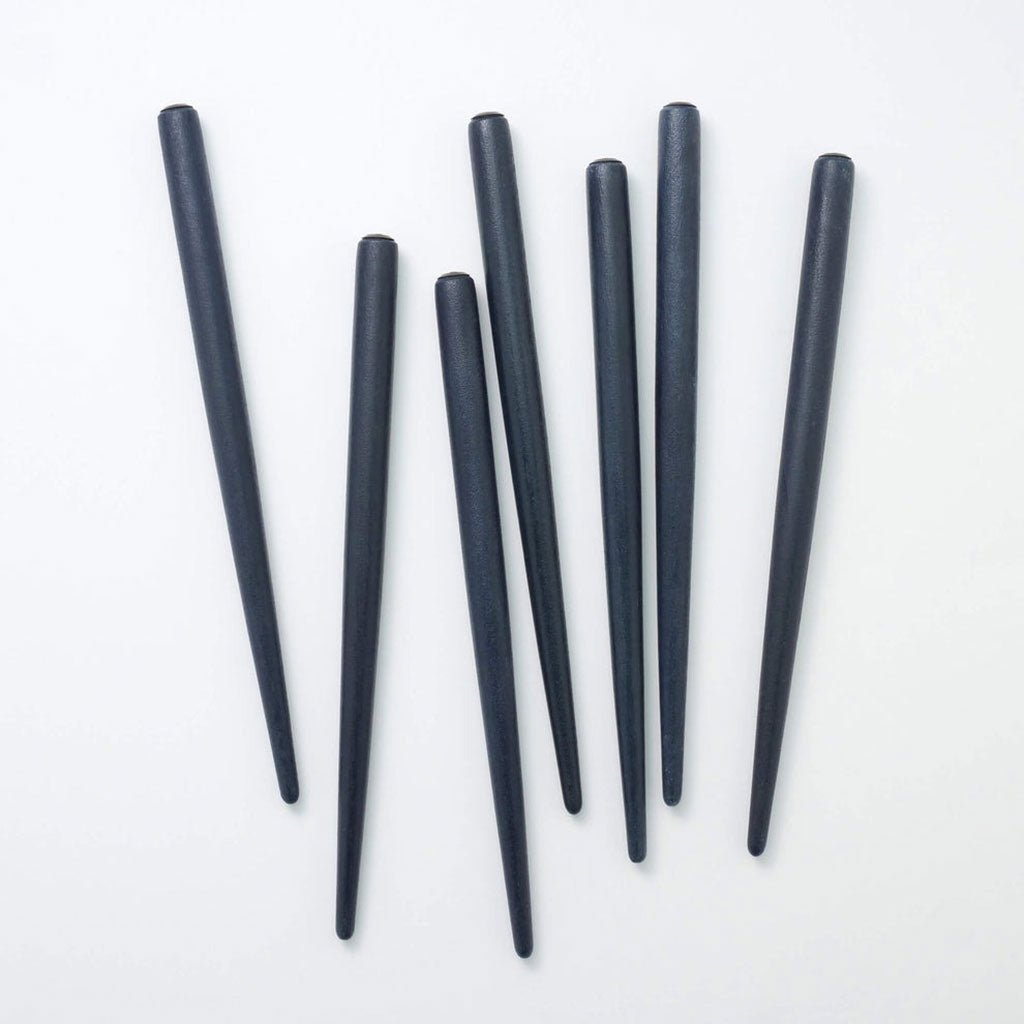 Pile of indigo dyed nib holders on white surface