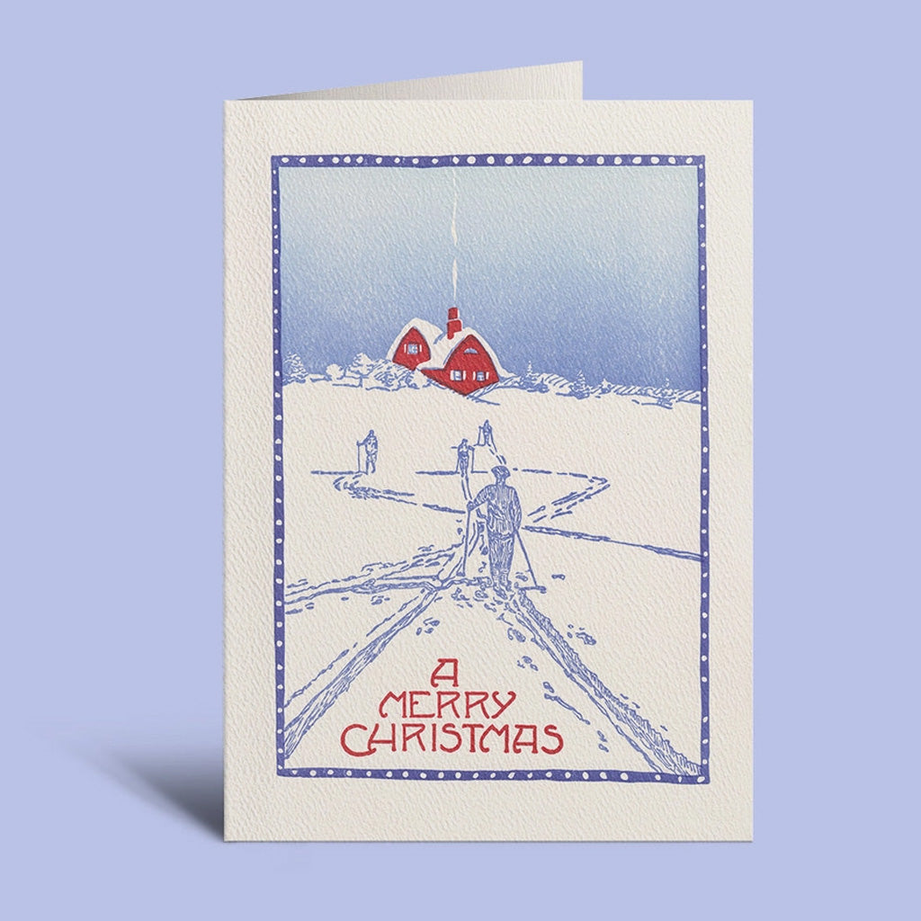 Holiday card with winter scene standing upright against light purple background.