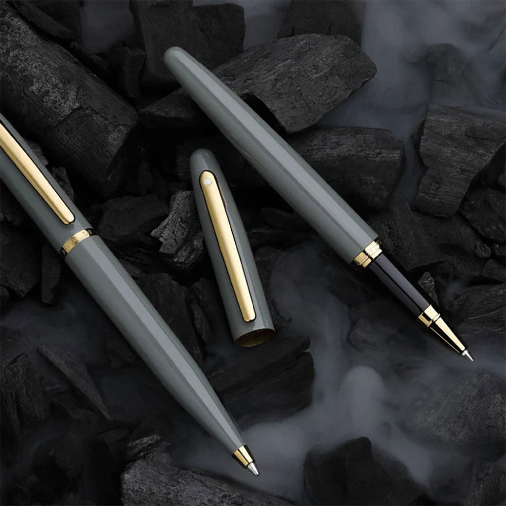 Two pens with gold accents on a dark, textured surface