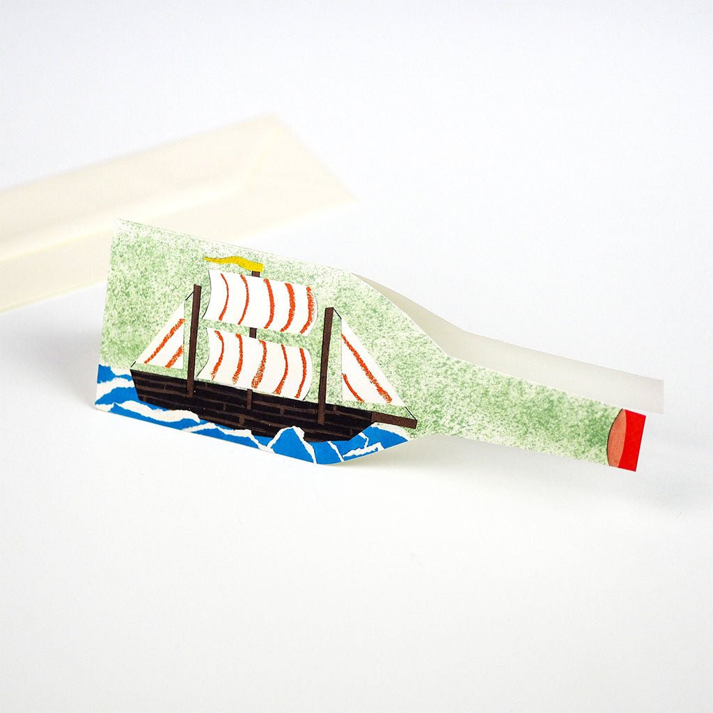 Ship in a bottle card standing upright with envelope in background