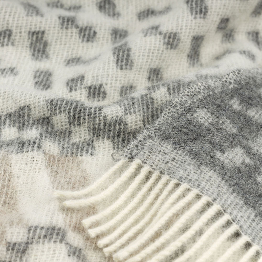 Close-up of a textured fabric with a checkered pattern and fringed edge.