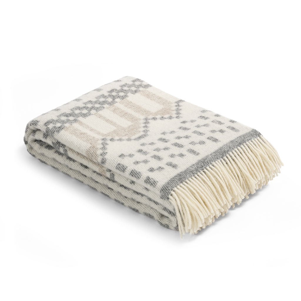 Folded blanket with a geometric pattern and fringed edge on a white background