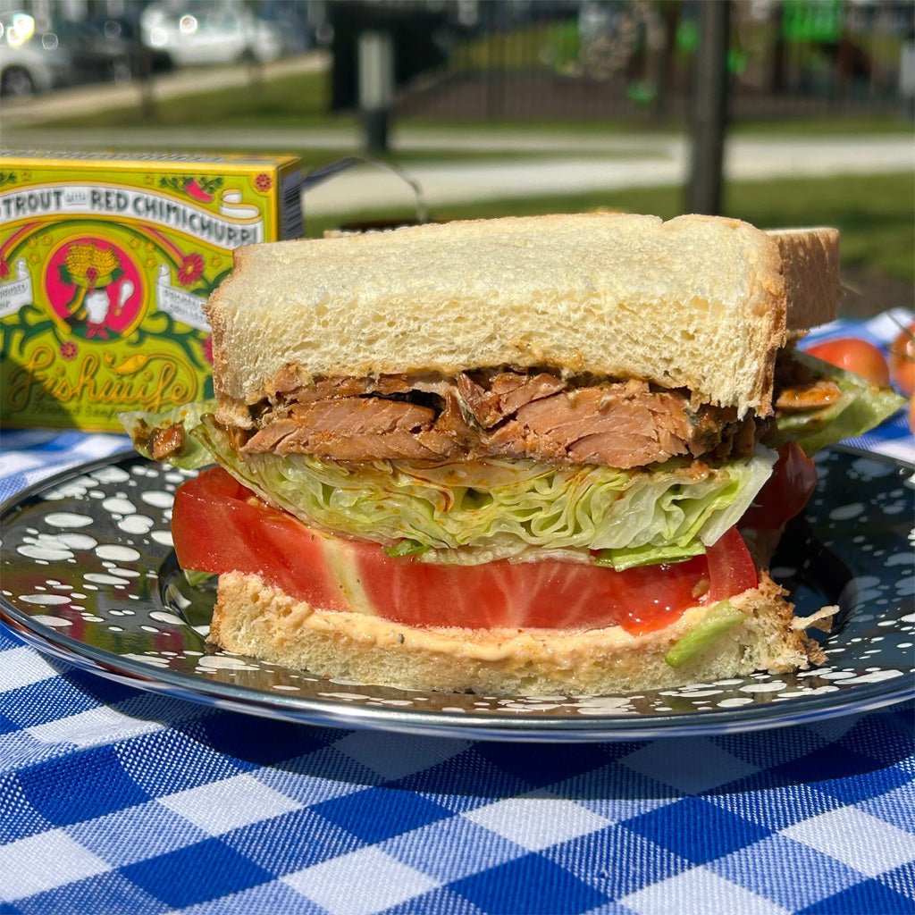 Sandwich with smoked trout and vegetables on picnic table