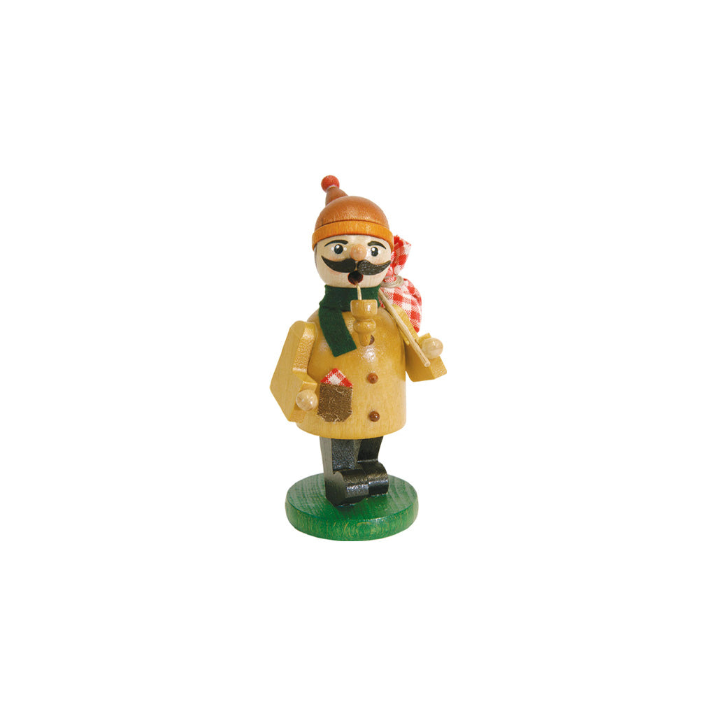 A small hand-painted wooden Christmas incense smoker figurine of a winter hiker, wearing a yellow coat, green scarf, orange hat, and black boots, standing on a green base against a white background.