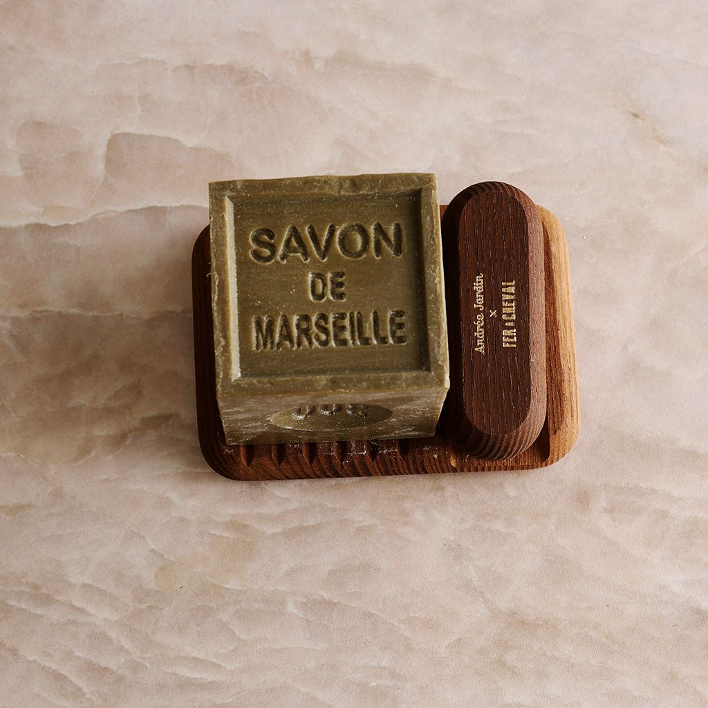 A wooden soap dish and nail brush with a cube of soap.