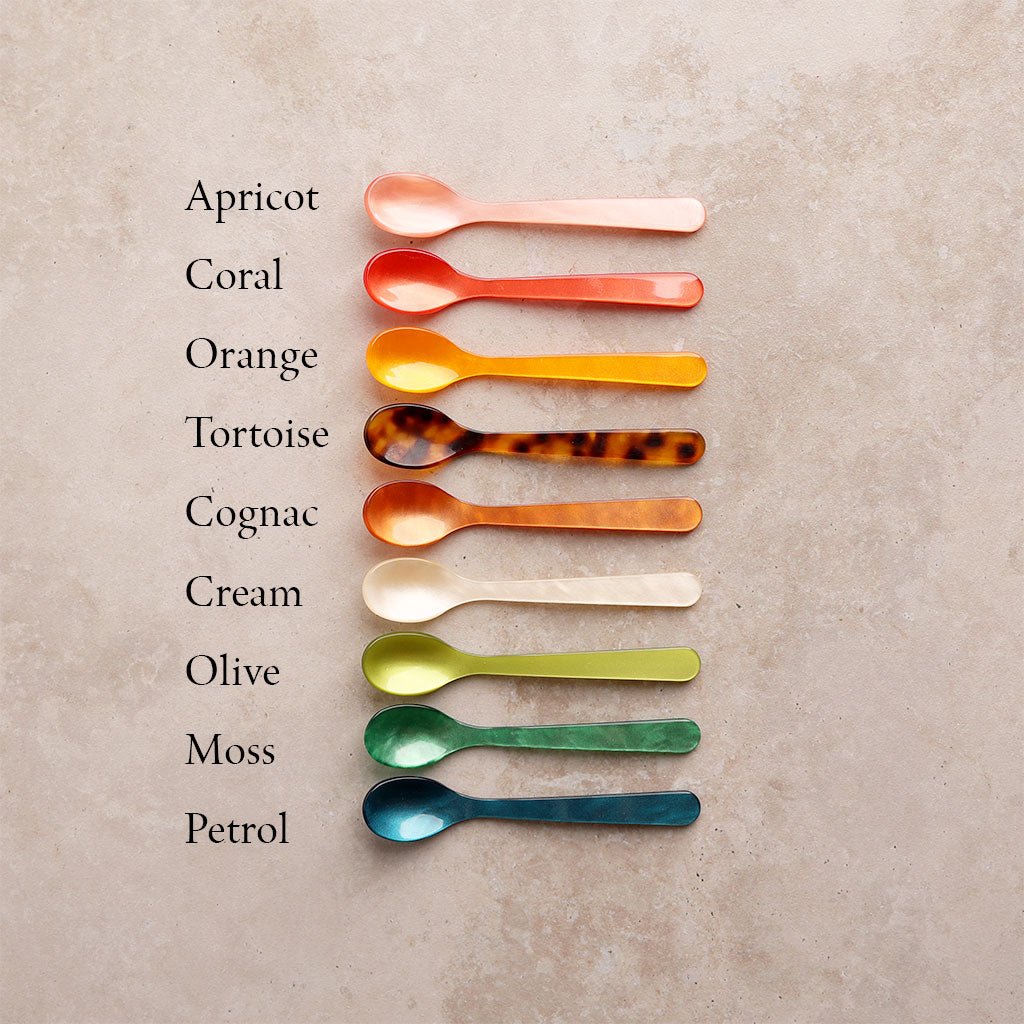 Set of colored acrylic spoons with labels on textured surface