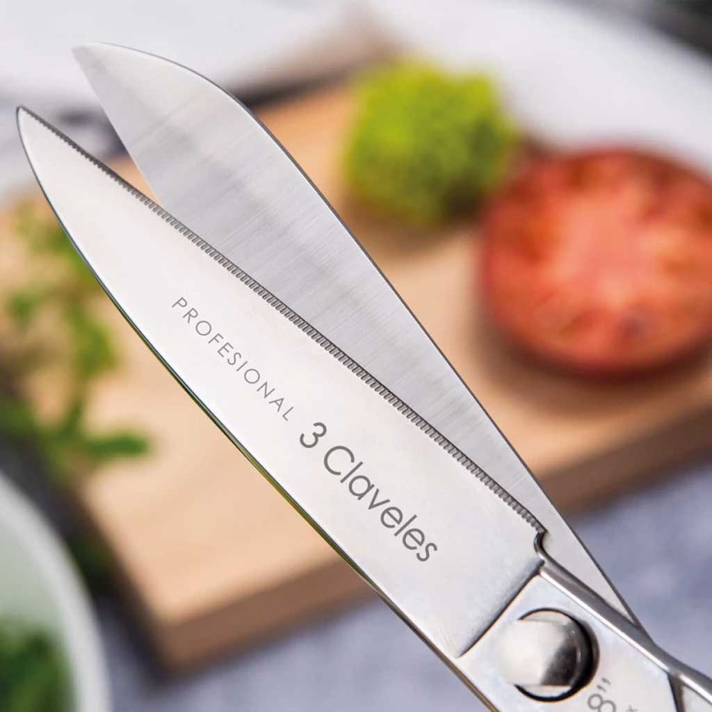 Micro-serrated scissors with '3 Claveles' branding on a blurred kitchen background