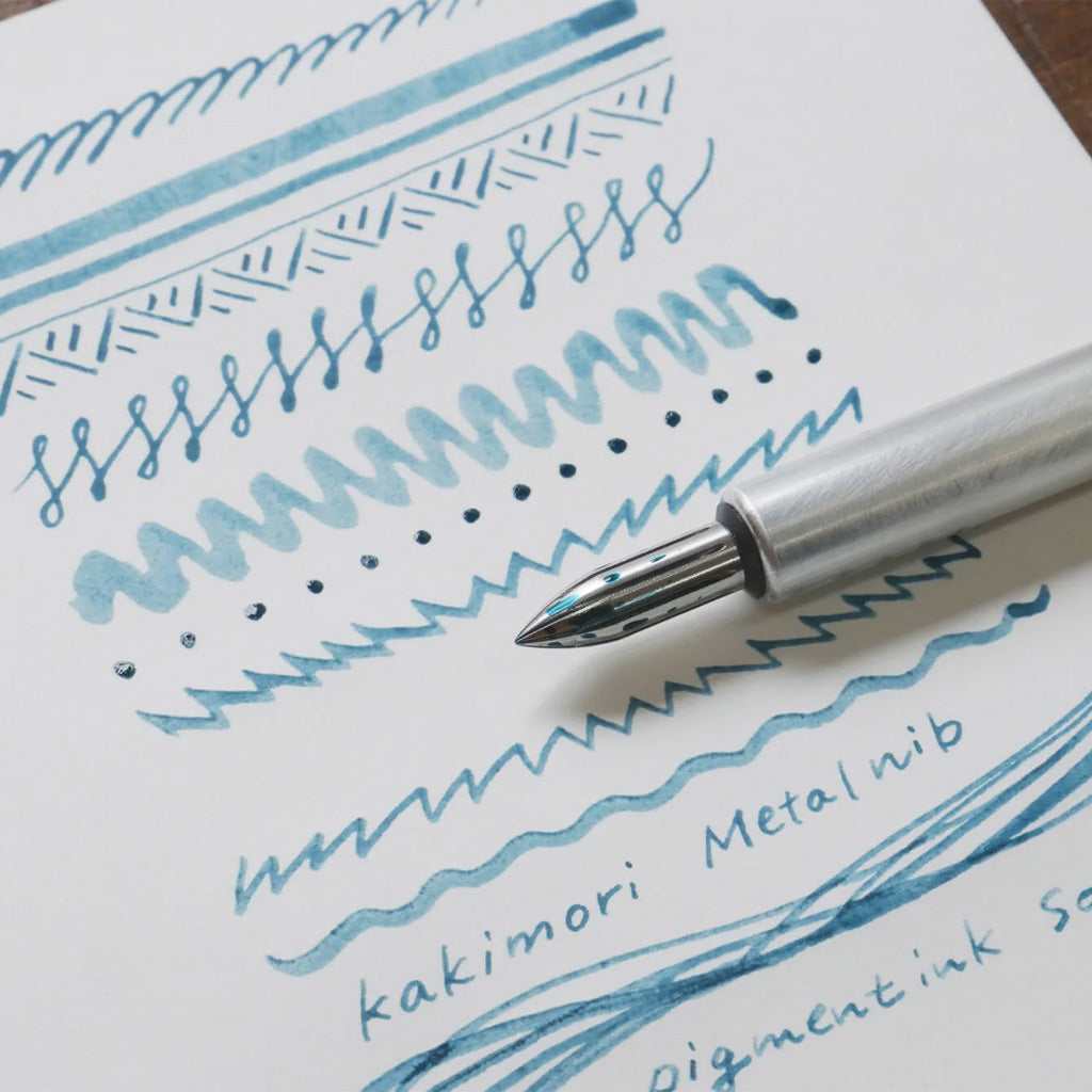 Kakimori stainless steel nib in metal dip pen with writing example in blue ink on white paper
