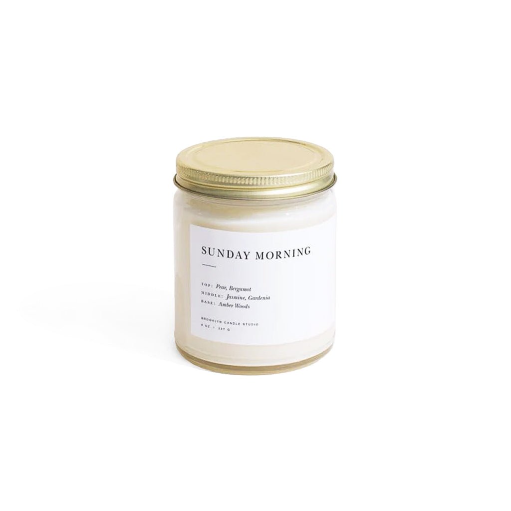 Candle jar labeled 'Sunday Morning' with a gold lid on a white background