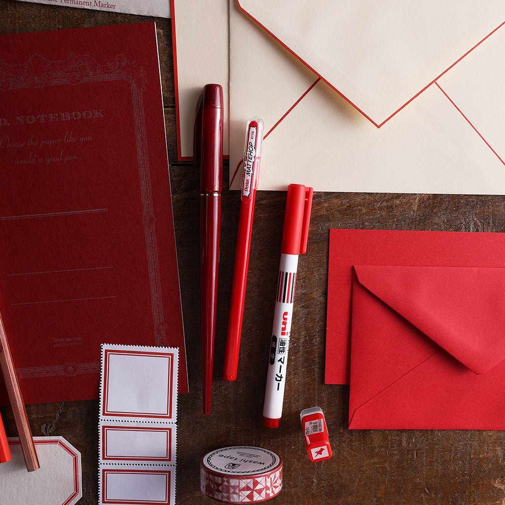 Red pens, notebook, envelopes, labels, and washi tape.