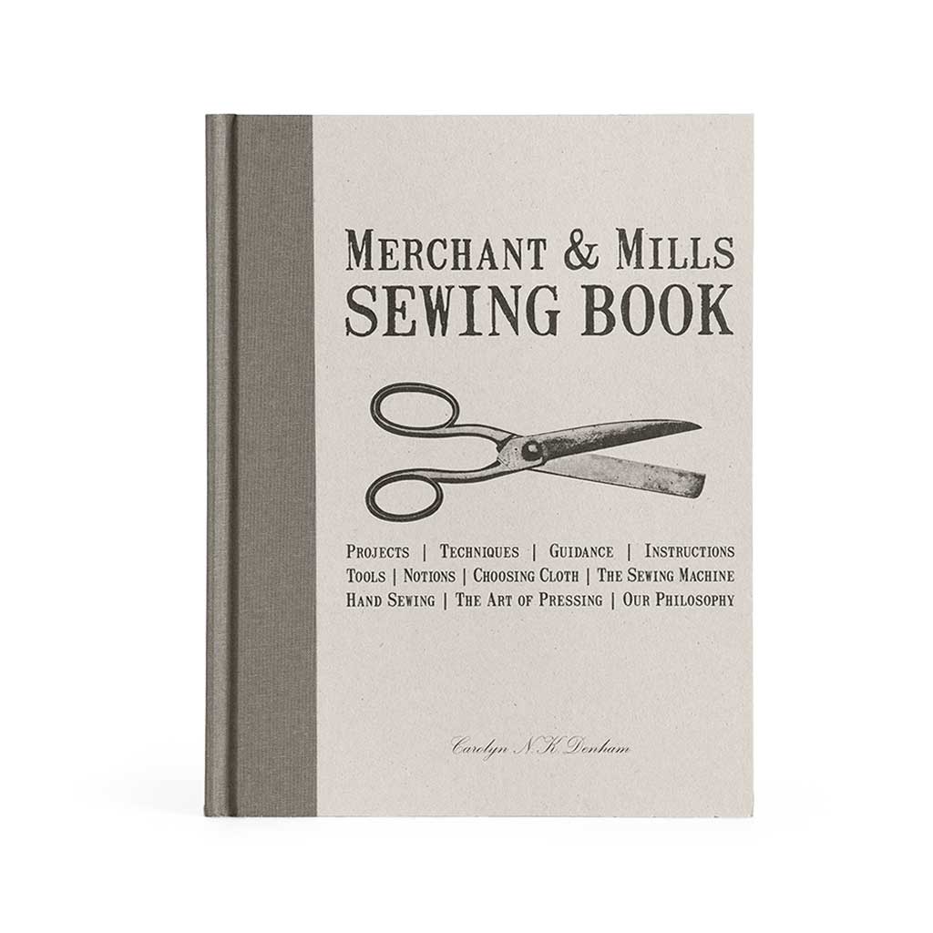 The cover of Merchant & Mills Sewing Book, showing a hardcover-bound book with an illustration of scissors on the front.