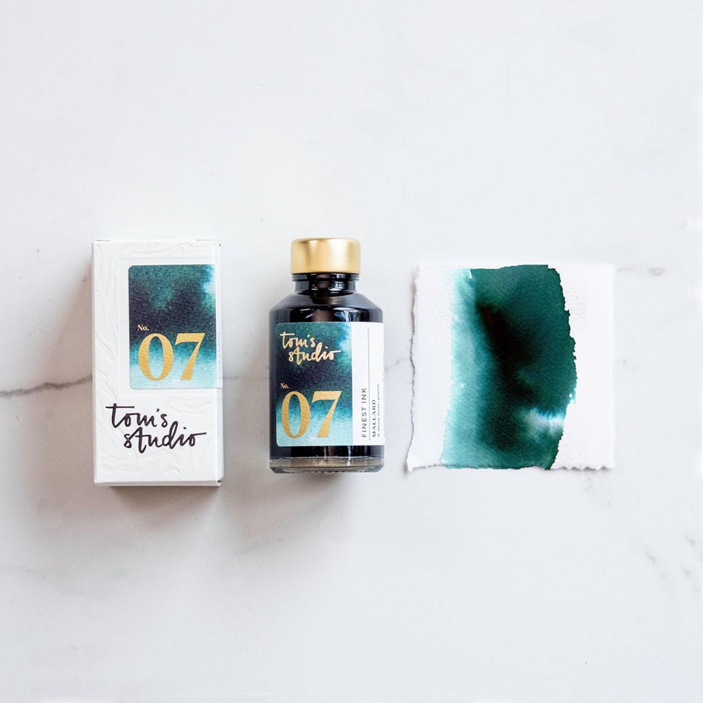 Tomi's Studio ink bottle with packaging and swatch on a light background