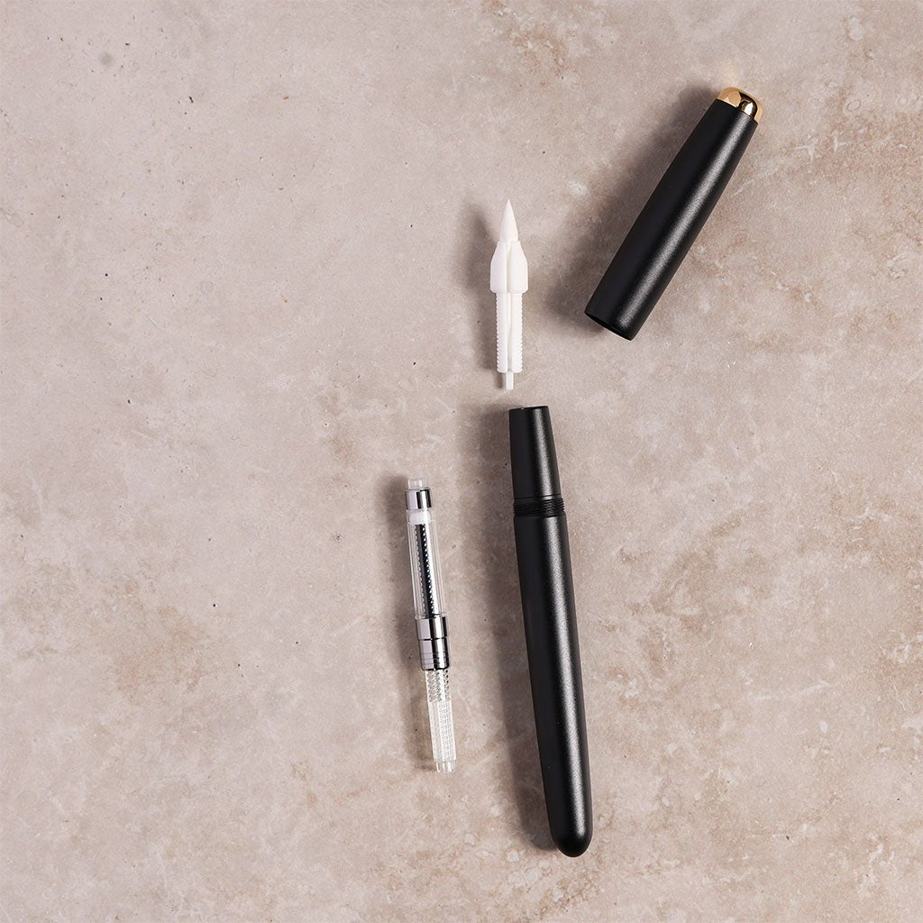 Black pen with components on a beige surface