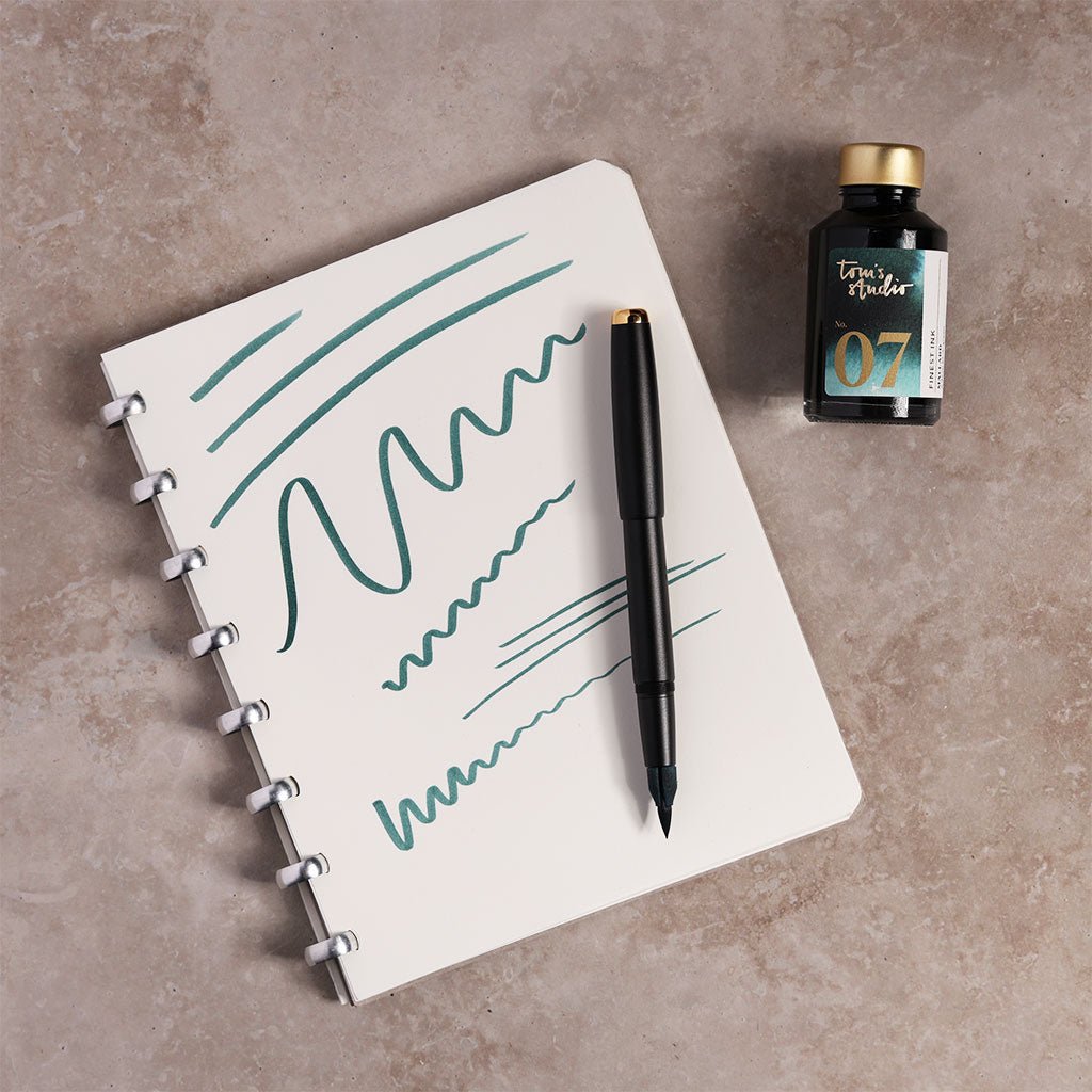 Notebook with pen and ink bottle on a textured surface