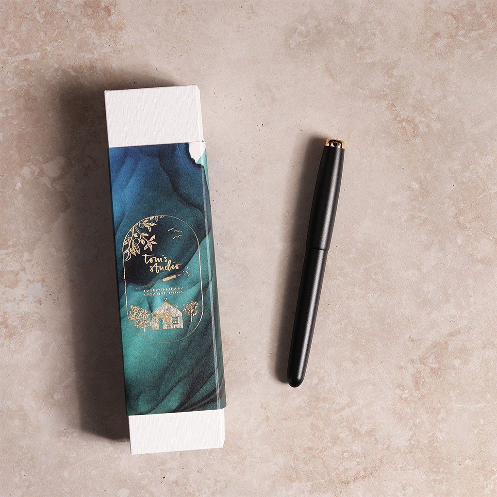 Black pen next to its packaging on a beige surface