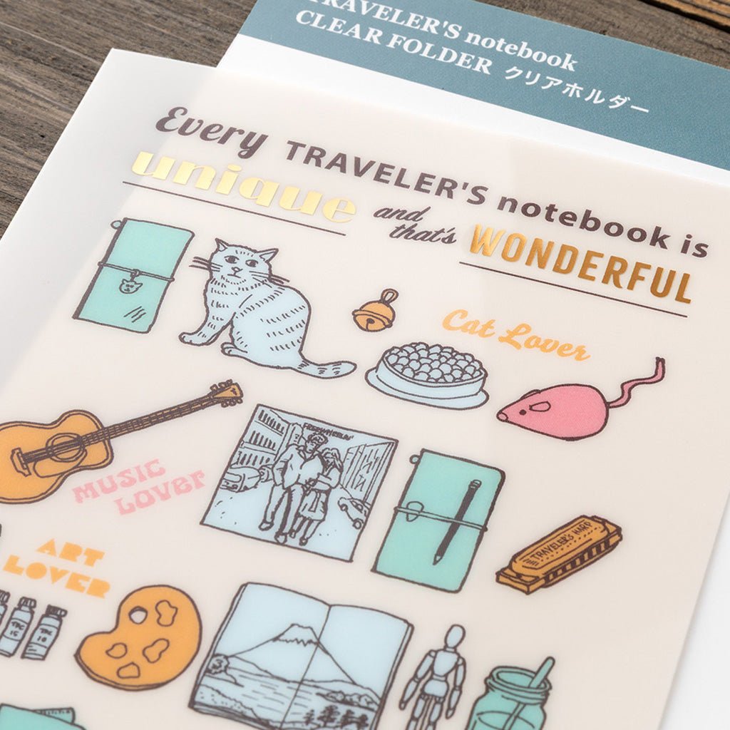 A cream-colored clear folder with colorful Traveler's Company illustrations on wooden background