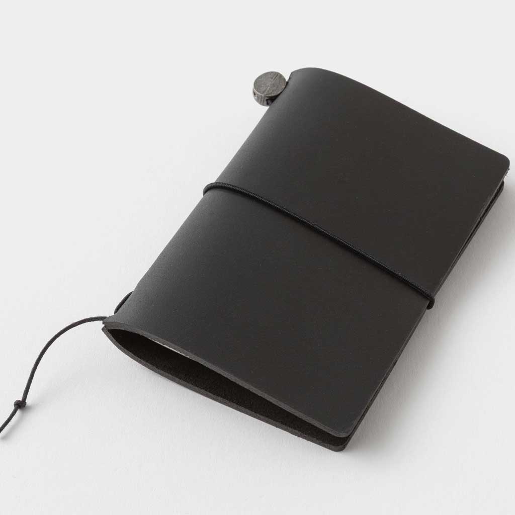 Closed black card-size leather notebook on white surface