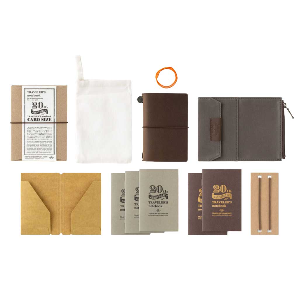 Brown traveler's notebook card-size set with accessories including notebooks, a pouch, and a pen on a white background