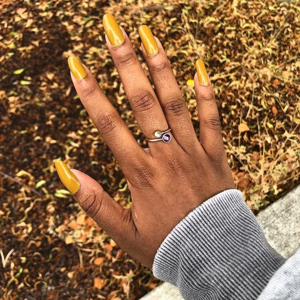 Hand wearing muted turmeric yellow nail polish