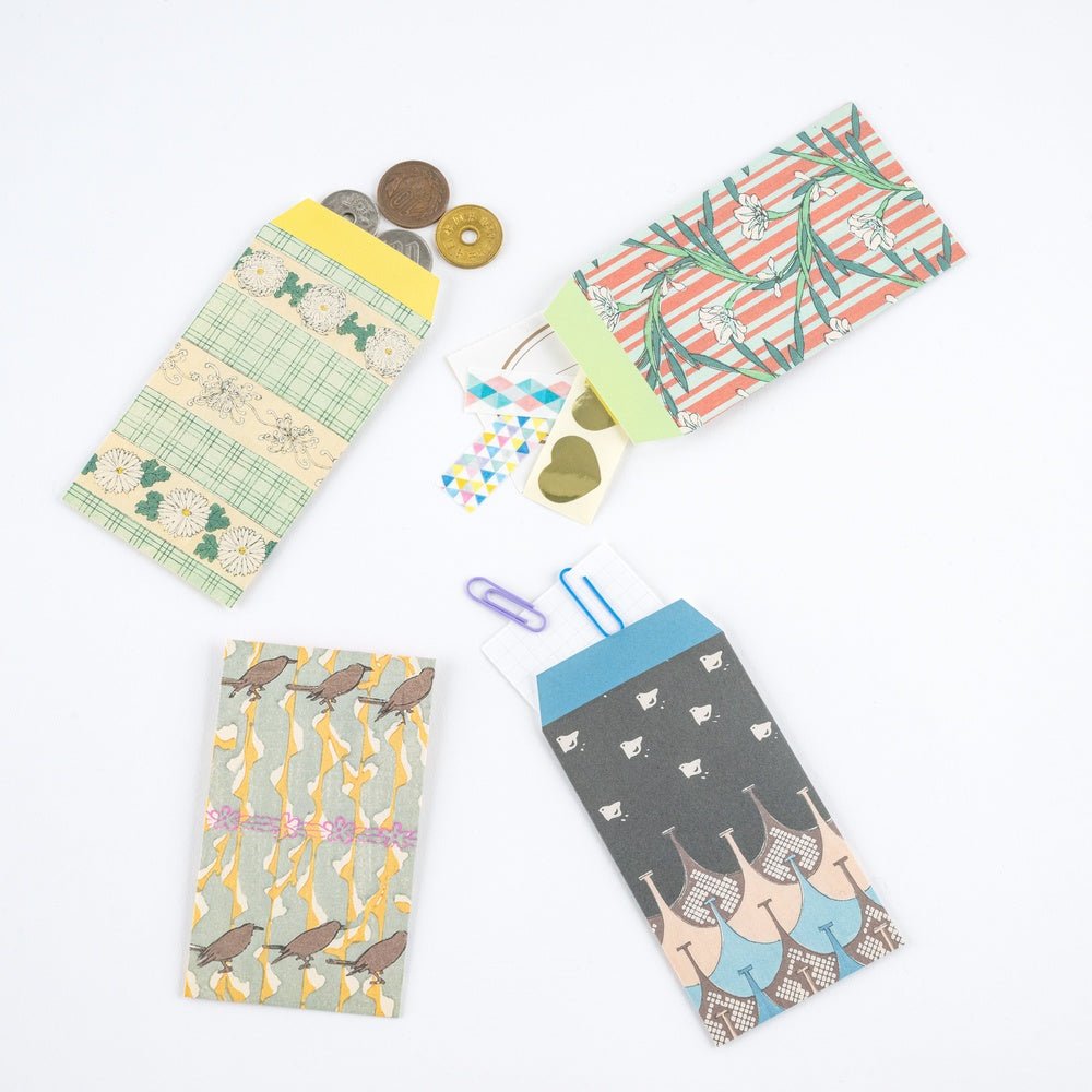 Set of four Hobonichi Unsodo mini paper envelopes with traditional Japanese woodblock print designs open and holding accessories and laying on white surface