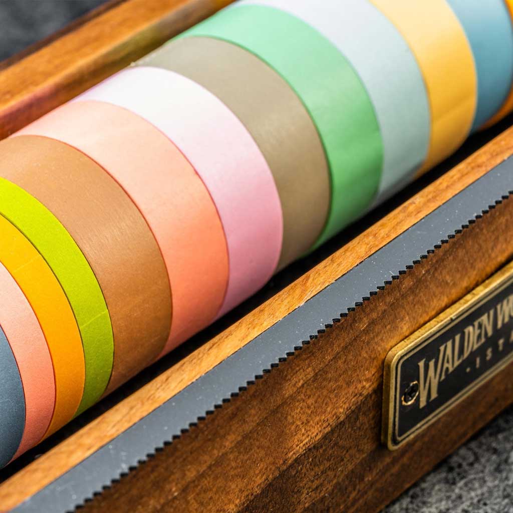 Large wooden washi tape dispenser with colorful tapes on dark background