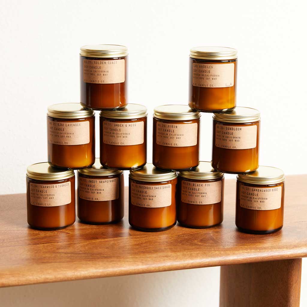 Collection of amber-colored candles with gold lids on a wooden surface.