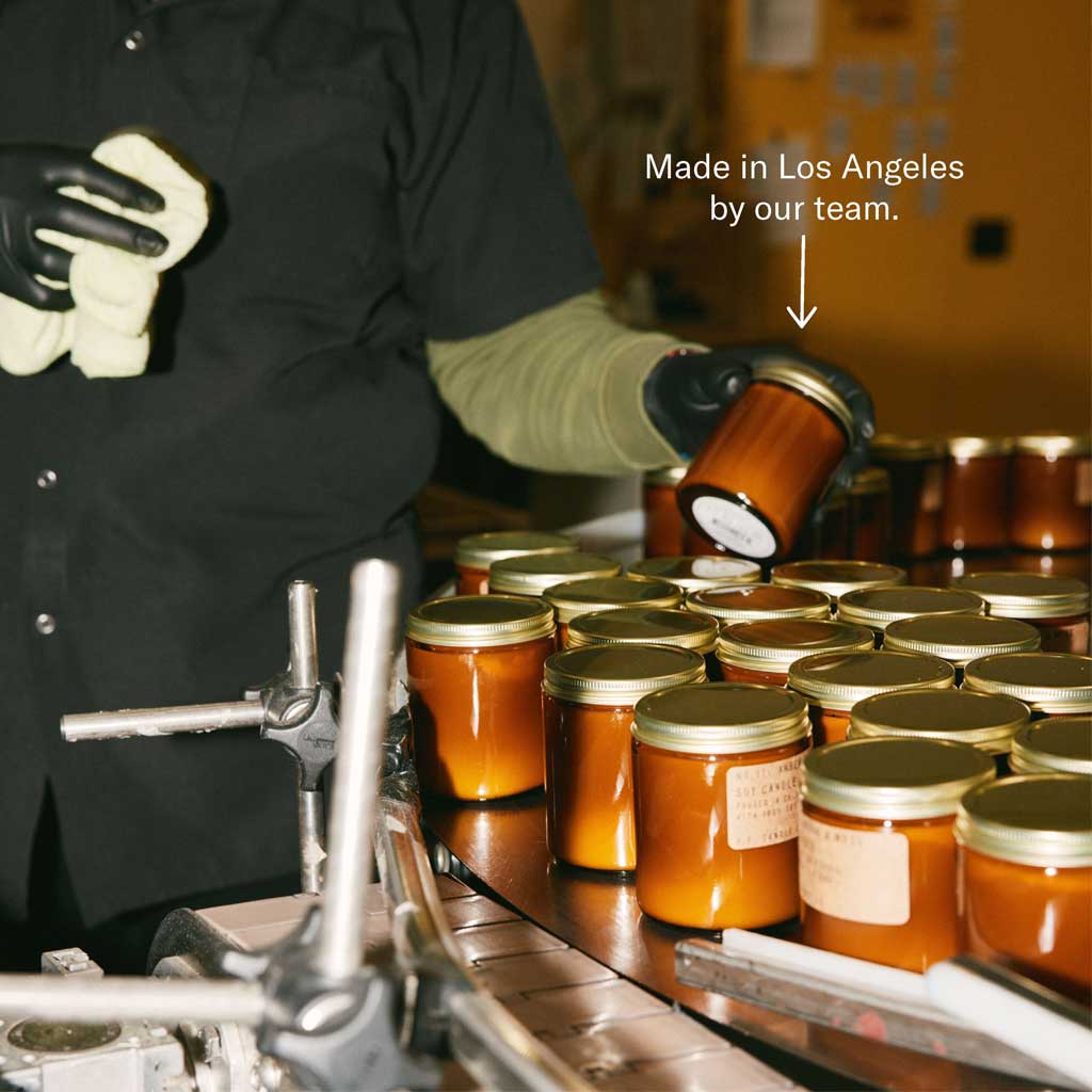 Person packaging candle jars with text 'Made in Los Angeles by our team.'