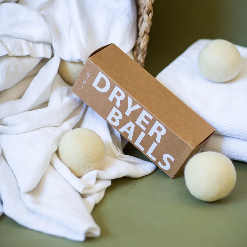 Dryer balls next to packaging on pile of sheets and towels on green couch