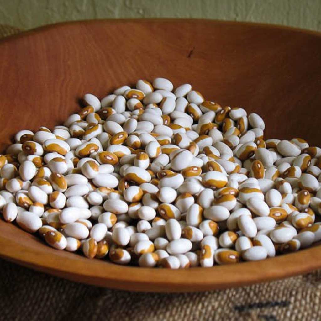 Wooden bowl filled with white and brown beans on a textured surface.
