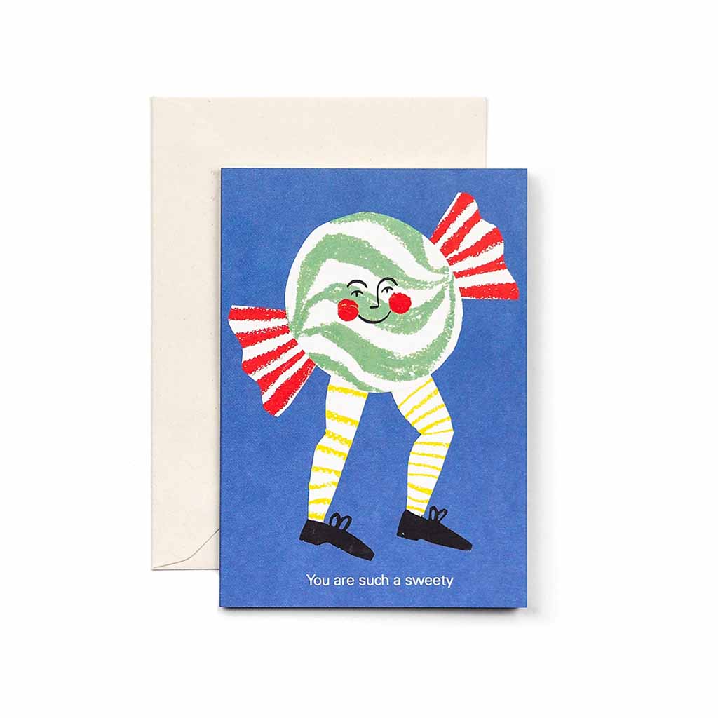 Greeting card with a smiling illustrated candy character on a blue background, reading “You are such a sweety,” shown with a cream envelope.