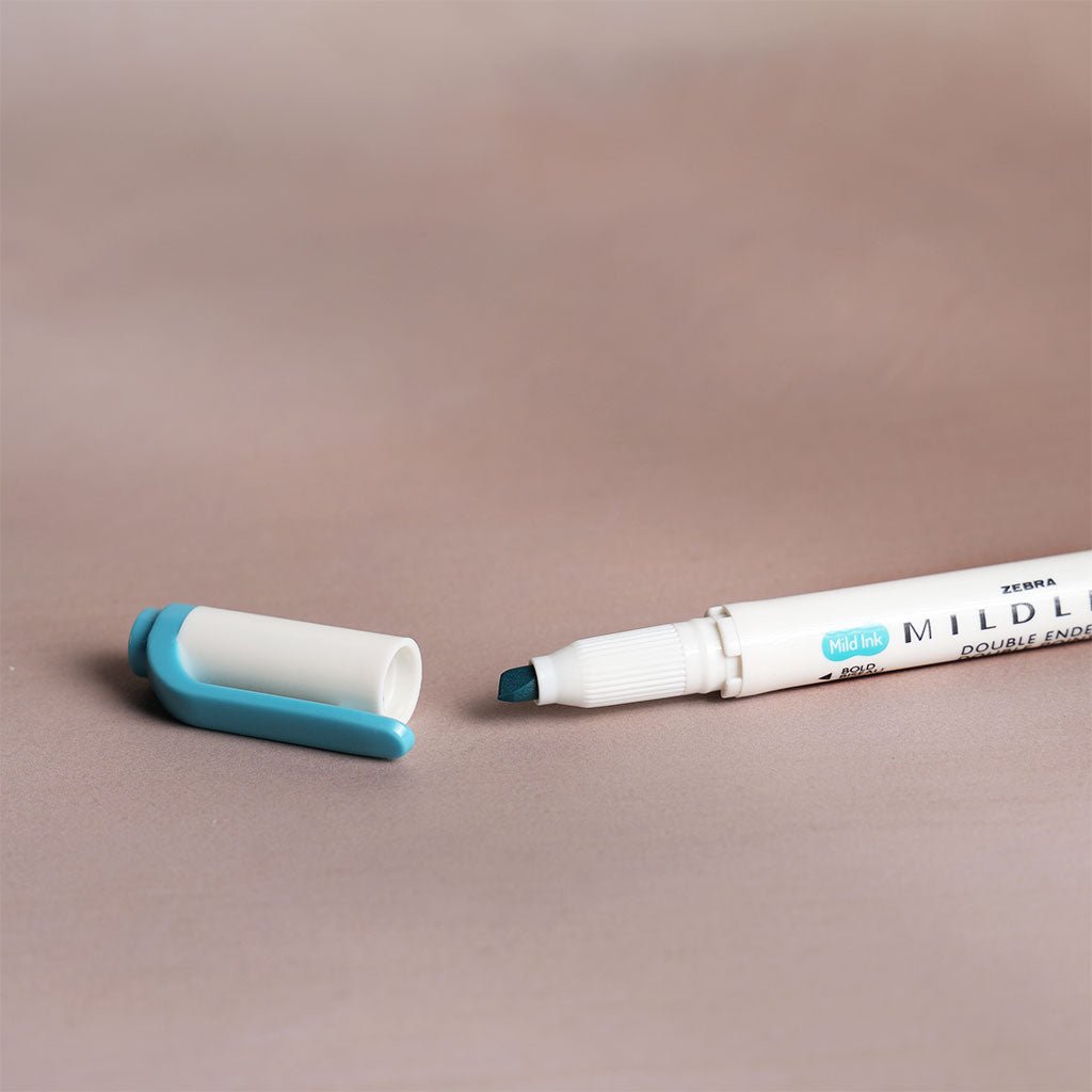 Double-ended marker with blue and black caps on a beige background