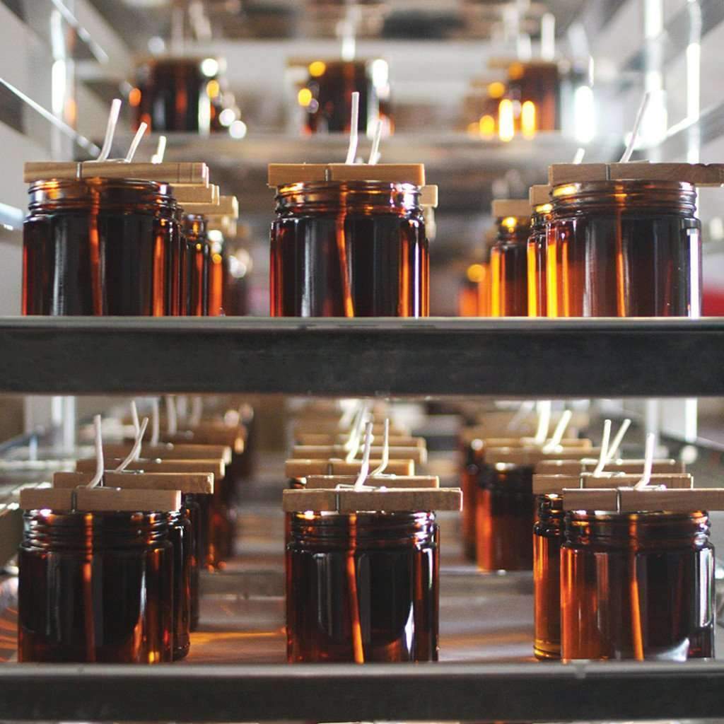 Batches of amber glass jars on metal shelves in a factory setting