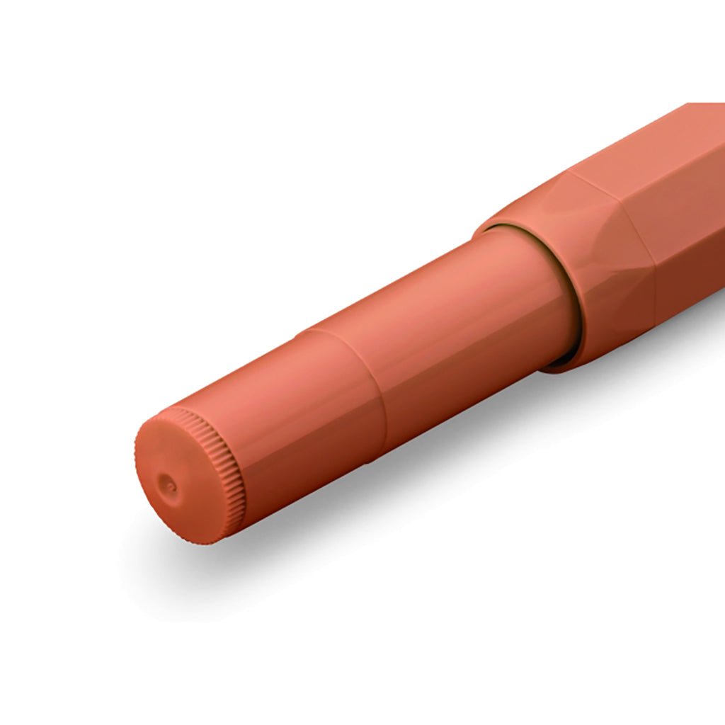 Closed orange fountain pen on white background