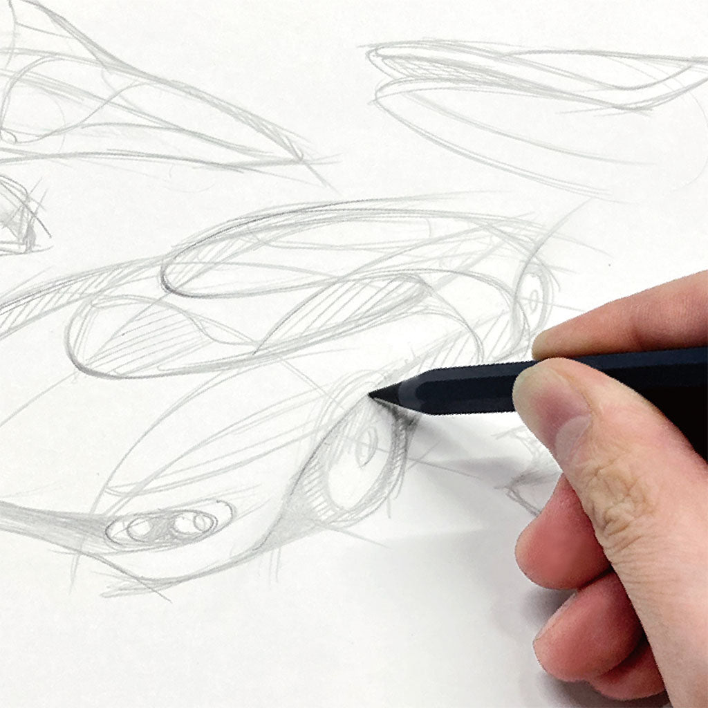 Hand holding a pen over a white paper with pencil sketches of abstract shapes.