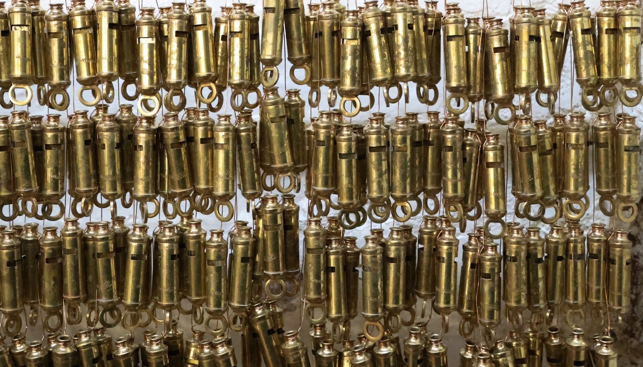 Rows of brass whistles hanging in factory.
