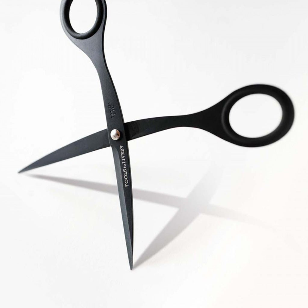 Black stainless steel scissors with 'TOOLS to LIVEBY' branding on blades on a light background.