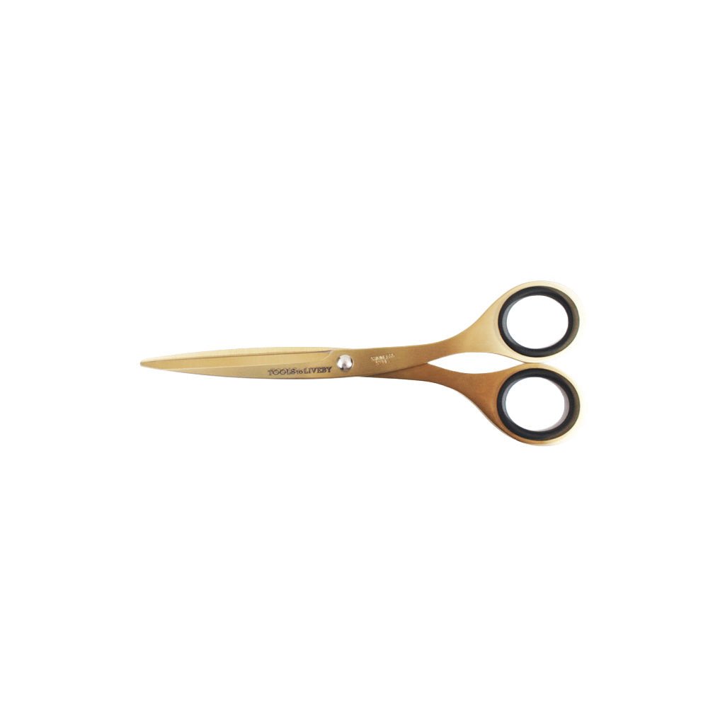 Gold-colored stainless steel scissors with black-rimmed finger loops on a white background.