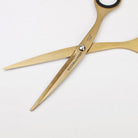 Gold-colored stainless steel scissors with 'TOOLS to LIVEBY' branding on blades on a light background.