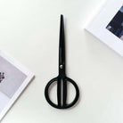Matte black scissors with rounded handles on white background