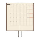 An open planner or journal showing a monthly calendar spread on warm cream grid pages.