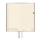 An open weekly planner with cream-colored pages, featuring a left column for Monday through Friday with time slots and brief prompts, a large right grid page for notes.