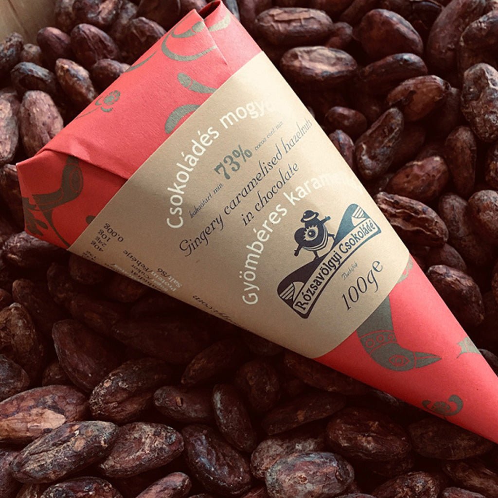 Bag of gingery caramelized hazelnuts on pile of chocolate-covered nuts.