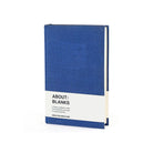 A blue linen-covered notebook or journal standing upright on a white background, with a white paper band around the lower middle that reads 'ABOUT: BLANKS'.
