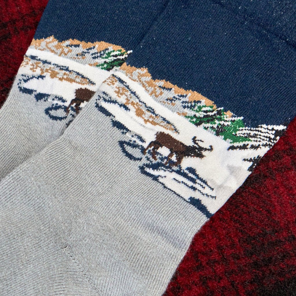 A close-up of a pair of knit socks with a winter landscape design. 