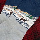 A close-up of a pair of knit socks with a winter landscape design. 
