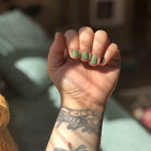 Hand with green nail polish and tattoos on a blurred background